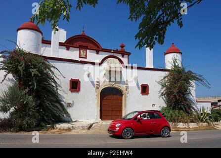 L'Italia, Puglia, Savelletri di Fasano, Fiat Cinquecento rosso passando davanti ad un bianco e chiesa rossa Foto Stock