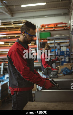 Lavoratore di sesso maschile la riparazione di una macchina con utensile Foto Stock