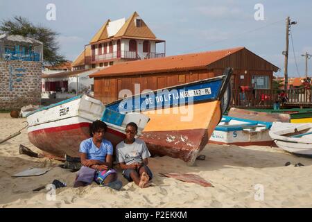 Capo Verde, Sal, Santa Maria, giovani uomini seduti davanti a barche di pescatori sulla spiaggia di Santa Maria Foto Stock