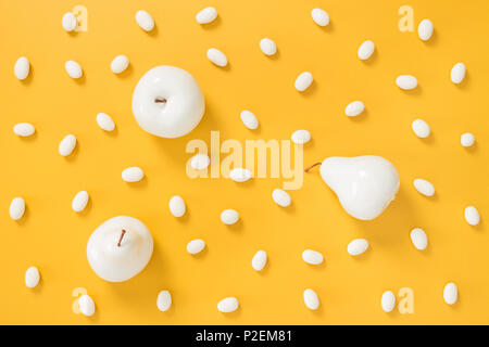 Il cioccolato bianco caramelle e frutta dipinta sul vivace sfondo giallo. Foto Stock