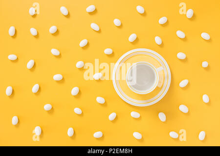 Il cioccolato bianco caramelle e tazzina sulla vibrante gioiosa sfondo giallo. Foto Stock