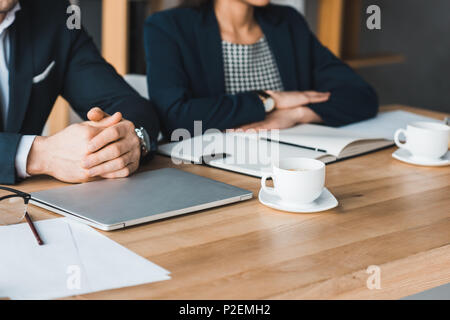 Colleghi di lavoro lavorare da tavolo con tazze da caffè in ufficio di luce Foto Stock