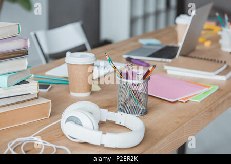 Close up di libri, cuffie, caffè, copybooks e portatile sul tavolo Foto Stock