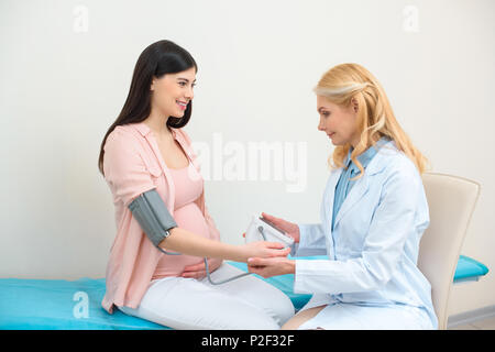Ostetrico ginecologo la misura della pressione del sangue di donna in stato di gravidanza Foto Stock