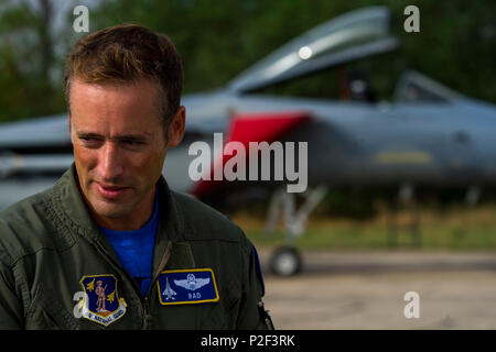 California Air National Guard Lt. Col. Matteo Ohman, un Expeditionary 194th Fighter Squadron F-15C Eagle fighter aircraft pilota, parla durante un'intervista con uno del suo squadrone di aerei in background sul flightline durante congiunto NATO air forze di polizia a Graf Ignatievo, Bulgaria, Sett. 9, 2016. Quattro la California e il Massachusetts ANGs' F-15Cs e circa 75 aviatori dal 194th distribuito EFS di Graf Ignatievo, Bulgaria, e saranno pronti come interceptor, pronti a reagire rapidamente ad eventuali violazioni e le infrazioni per le operazioni di polizia di spazio aereo bulgaro sett. 9-16, 2016. Lo squadrone Foto Stock