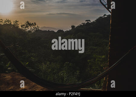 Il tramonto visto da un punto di vista amaca oltre la giungla in Minca, Colombia con la città di Santa Marta debolmente a distanza Foto Stock