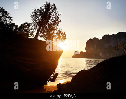 Rocciatore in silhouette a Tonsai spiaggia al tramonto a Krabi, Thailandia Foto Stock