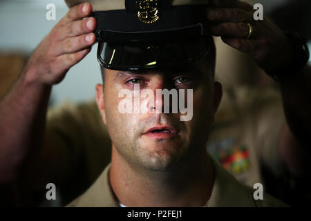 Chief Operations Specialist Nate Klimis trattiene le lacrime come chief petty officer coperchio è posto in cima al suo capo durante una CPO pinning cerimonia a bordo della USS Bataan (LHD-5) sett. 16, 2016. Klimis detto diventando un capo è qualcosa che nessuno può fare da solo. "La prima volta che siamo venuti in marina, molti di noi non sanno cosa significa tenere il peso del dispositivo di ancoraggio," ha detto del suo nuovo titolo. Dopo 18 anni di servizio Klimis dice di essere pronto per la responsabilità di "il capo." (U.S. Marine Corps foto di Sgt. Matthew Callahan) Foto Stock