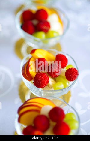 Una sana frutta fresca e bacche con insalata di lamponi, ananas, banana, uva, mele e su un tavolo all'aperto delle fette di mela in vetro.backgro di frutta Foto Stock
