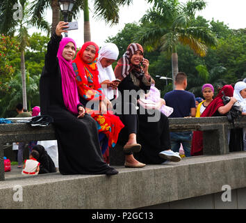 Un gruppo di donne musulmane prendendo un selfie. Filippini e musulmani stranieri di raccogliere al Quirino Grandstand a Manila per festeggiare la fine del Ramadan. Essi celebrare con preghiere, cibo e divertimento, soprattutto per la famiglia. Eid al-Fitr è un importante festa religiosa celebrata dai musulmani di tutto il mondo che segna la fine del Ramadan, islamica del sacro mese del digiuno. Foto Stock