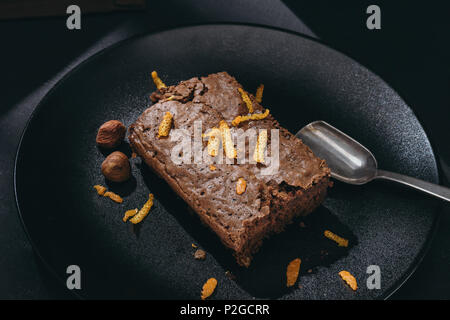 Close-up shot di torta al cioccolato con la scorza di arancia sulla piastra nera Foto Stock