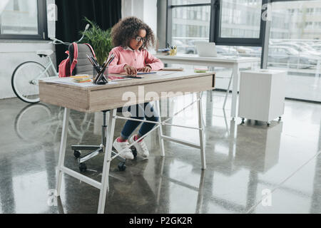 Poco African American Girl imprenditrice con capelli ricci lavora in un ufficio moderno Foto Stock