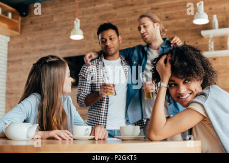 Due uomini ubriachi sono diffidenti nei confronti delle giovani donne in seduta cafe Foto Stock