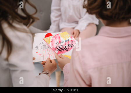 Ritagliato shot dei bambini presentando la festa della mamma biglietto di auguri per la madre Foto Stock