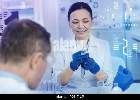 Biologo calma sorridendo mentre guardando il razzo in un tubo di prova Foto Stock