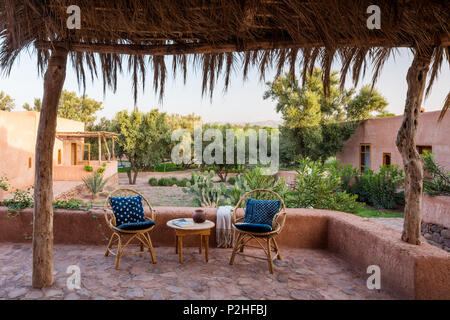 Una coppia di sedie di rattan sulla terrazza giardino con muri di terra, erbe e marocchine piante selvatiche. Garden design di Arnaud Casaus Foto Stock