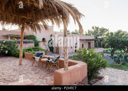 Una coppia di sedie di rattan sulla terrazza giardino con muri di terra, erbe e marocchine piante selvatiche. Garden design di Arnaud Casaus Foto Stock