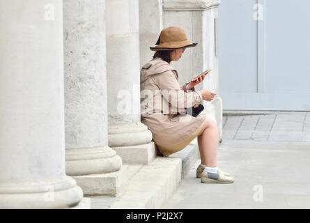 Donna Giapponese seduto con il suo telefono cellulare, Whitehall, Londra, Inghilterra, Regno Unito. Foto Stock