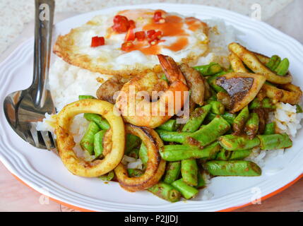 Stir-frittura di pesce al curry e uovo fritto sul riso Foto Stock