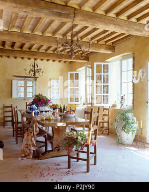 Rustiche travi a soffitto nel paese toscano sala da pranzo con una semplice tavola di legno e sedie ladderback Foto Stock