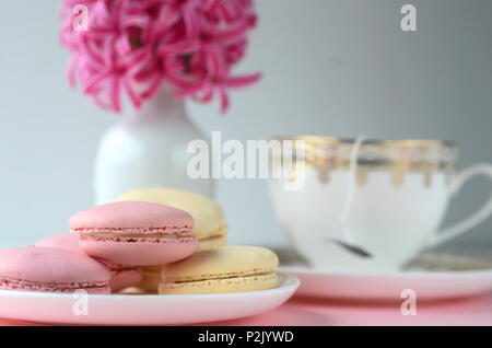 Rosa luminoso giacinto con French macarons, una tazza di caffè e gold nero cartoleria.femminile business lifestyle & Lavoro da casa concetto. La molla del tema. Foto Stock