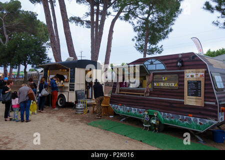 Le persone con le loro famiglie attorno ad un festival locale con diversi carrelli di cibo, in estate per vacanze di Foto Stock