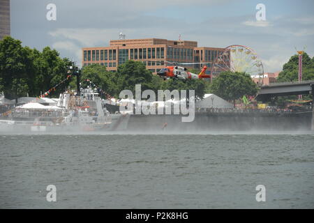 Un Coast Guard aviation tecnico di sopravvivenza (salvataggio nuotatore) è issato al di fuori del fiume Willamette vicino al centro cittadino di Portland, Ore., waterfront durante una dimostrazione di salvataggio, 9 giugno 2018. L'equipaggio di dimostrazione è stata parte del Festival di Rose e della Flotta della Marina Militare settimana di festeggiamenti. Stati Uniti Coast Guard foto di Sottufficiali di prima classe Levi leggere. Foto Stock