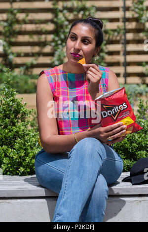 Donna di mangiare Doritos al di fuori Foto Stock