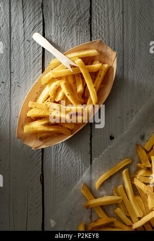 Patate fritte su carta ciotola con forcella in legno Foto Stock