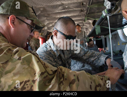 Stati Uniti Esercito personale di riserva Sgt. Justin Gaughan, un tecnico di volo assegnato a 158Reggimento di aviazione dal nuovo secolo centro aria, Kansas, incarica Senior Airman Jeffrey Balino, un odontotecnico assegnato alla 442d Medical Squadron, come bloccare una figliata su lettiera cinghie in un CH-47 elicottero Chinook, Giugno 10, 2018 a Whiteman Air Force Base, Mo. riserva cittadino aviatori praticata cucciolate di fissaggio all'interno dell'elicottero in caso di evacuazione medica. (U.S. Air Force foto di Senior Airman Missy Sterling) Foto Stock