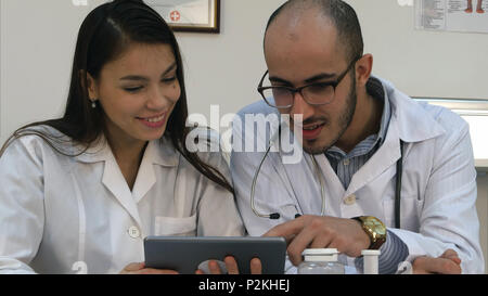 Due medici guardando qualcosa di divertente sulla tavoletta e ridere Foto Stock