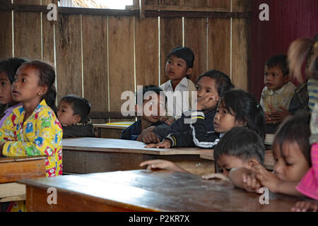 Bambini cambogiani seduto in una povera in Aula per ascoltare il loro insegnante nella risma scuola locale. Un ragazzo getta i suoi occhi per la ragazza accanto a lui. Foto Stock