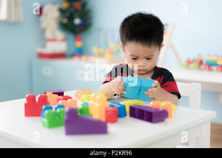 Adorabili Asian Toddler baby boy seduti su una sedia e giocare con blocco colore giocattoli a casa. Foto Stock