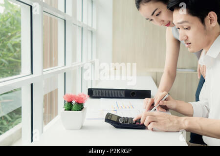 Asian business giovane lavorando insieme sul progetto al moderno ufficio di avvio. Senior business donna suggerimento nuovo lavoratore Uomo alla scrivania in ufficio. Foto Stock