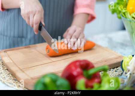 Mano con il taglio della lama di carota. La donna si prepara il cibo in tavola. Chef deliziosa cena. Lavoro che richiede abilità. Foto Stock