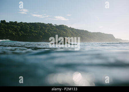 Giovane uomo nuotare sulla tavola da surf sulla giornata di sole Foto Stock