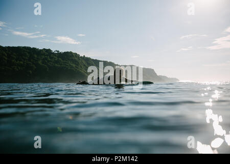 Uomo bello nuotare sulla tavola da surf sulla giornata di sole Foto Stock