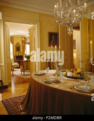 Cristallo di antiquariato lampadario di vetro sopra la tabella impostata per la cena con le candele accese nella elegante sala da pranzo Francese Foto Stock