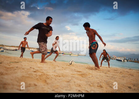 I giovani locali che giocano a calcio sulla spiaggia Trawangan, Gili Trawangan, Lombok, Indonesia Foto Stock