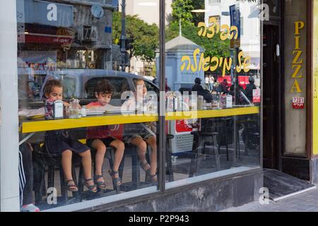 Israele, Tel Aviv, downtown, Herzl street, i bambini a tavola dietro una vetrina in un ristorante fast food Foto Stock