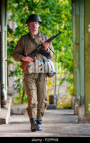 Un soffice come l'aria giocatore indossa tedesco orientale 1975, Junior Non-Commissioned ufficiali uniforme con un AK-47, il Kalashnikov (Poste ny modello) Foto Stock