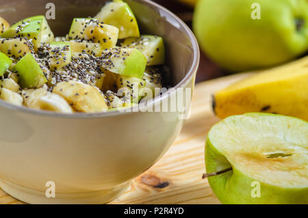Sana Colazione ciotola: fiocchi d'avena con banana, mela verde, sesamo e semi di Chia Foto Stock