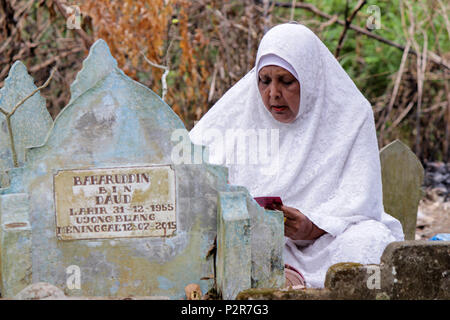 Lhokseumawe, Indonesia. 16 Giugno, 2018. Una donna visto pregare accanto a un grave durante il pellegrinaggio.musulmani visto con i loro parenti' grave durante un pellegrinaggio al cimitero pubblico in città Lhokseumawe. La maggior parte dei musulmani in Aceh già fatto l'ultima tomba pellegrinaggio prima di entrare nel sacro mese del Ramadan e il giorno di Eid al-Fitr, a pregare per le famiglie di coloro che sono morti. Credito: Maskur ha SOPA/images/ZUMA filo/Alamy Live News Foto Stock