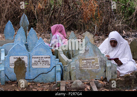 Lhokseumawe, Indonesia. 16 Giugno, 2018. Le donne visto pregare accanto a un grave durante il pellegrinaggio.musulmani visto con i loro parenti' grave durante un pellegrinaggio al cimitero pubblico in città Lhokseumawe. La maggior parte dei musulmani in Aceh già fatto l'ultima tomba pellegrinaggio prima di entrare nel sacro mese del Ramadan e il giorno di Eid al-Fitr, a pregare per le famiglie di coloro che sono morti. Credito: Maskur ha SOPA/images/ZUMA filo/Alamy Live News Foto Stock