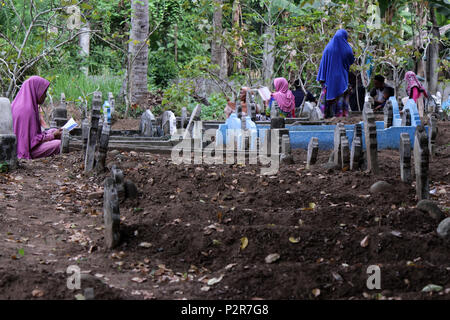 Lhokseumawe, Indonesia. 16 Giugno, 2018. Una donna visto pregare accanto a un grave durante il pellegrinaggio.musulmani visto con i loro parenti' grave durante un pellegrinaggio al cimitero pubblico in città Lhokseumawe. La maggior parte dei musulmani in Aceh già fatto l'ultima tomba pellegrinaggio prima di entrare nel sacro mese del Ramadan e il giorno di Eid al-Fitr, a pregare per le famiglie di coloro che sono morti. Credito: Maskur ha SOPA/images/ZUMA filo/Alamy Live News Foto Stock