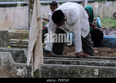 Lhokseumawe, Indonesia. 16 Giugno, 2018. Un uomo musulmano si vede guardando su un relativo grave durante il pellegrinaggio.musulmani visto con i loro parenti' grave durante un pellegrinaggio al cimitero pubblico in città Lhokseumawe. La maggior parte dei musulmani in Aceh già fatto l'ultima tomba pellegrinaggio prima di entrare nel sacro mese del Ramadan e il giorno di Eid al-Fitr, a pregare per le famiglie di coloro che sono morti. Credito: Maskur ha SOPA/images/ZUMA filo/Alamy Live News Foto Stock