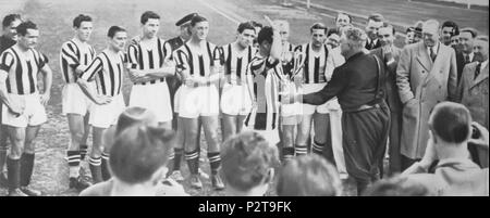 . Italiano: Torino, stadio municipale Benito Mussolini, 8 maggio 1938. Il capitano della Juventus, Mario Varglien (MI), intento a eseguire il saluto romano venire prassi nell'Italia fascista, riceve dal presidente della Federazione Italiana Giuoco Calcio, generale Giorgio Vaccaro, il trofeo della Coppa Italia 1937-38 al termine della vittoriosa finale di ritorno contro i concittadini del Torino (2-1): si trattò del primo successo nella competizione per la squadra bianconera, nonché della prima finale di Coppa Italia assegnata in una Stracittadina (Torino). 8 maggio 1938. 44 sconosciuto Juventus - Coppa Foto Stock