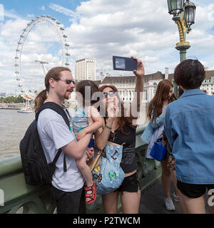 Londra, UK: Luglio 25, 2016: turisti scattare una fotografia sul Westminster Bridge con una vista del fiume Tamigi dietro di loro. Foto Stock