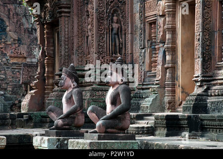 Angkor Cambogia, custodi di scimmia seduto all'entrata del santuario al decimo secolo il Banteay Srei tempio ornato di parete scolpita in background Foto Stock