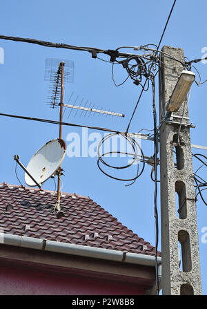 Palo elettrico e antenne sul tetto di una casa Foto Stock